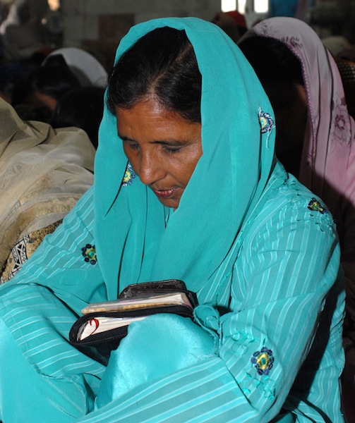 A Pakistani woman prays with her Bible. Photo: United Bible Societies.