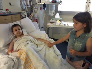 Harrison is comforted by sister Chloe while in ICU. 
