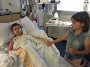 Harrison is comforted by sister Chloe while in ICU. 