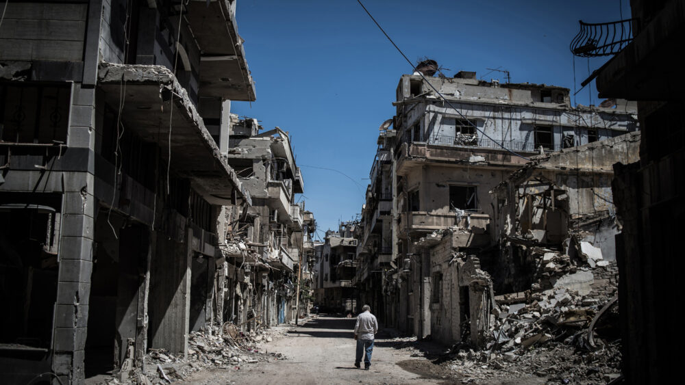 A Syrian refugee walks among severely damaged buildings in downtown Homs, Syria, on June 3, 2014.