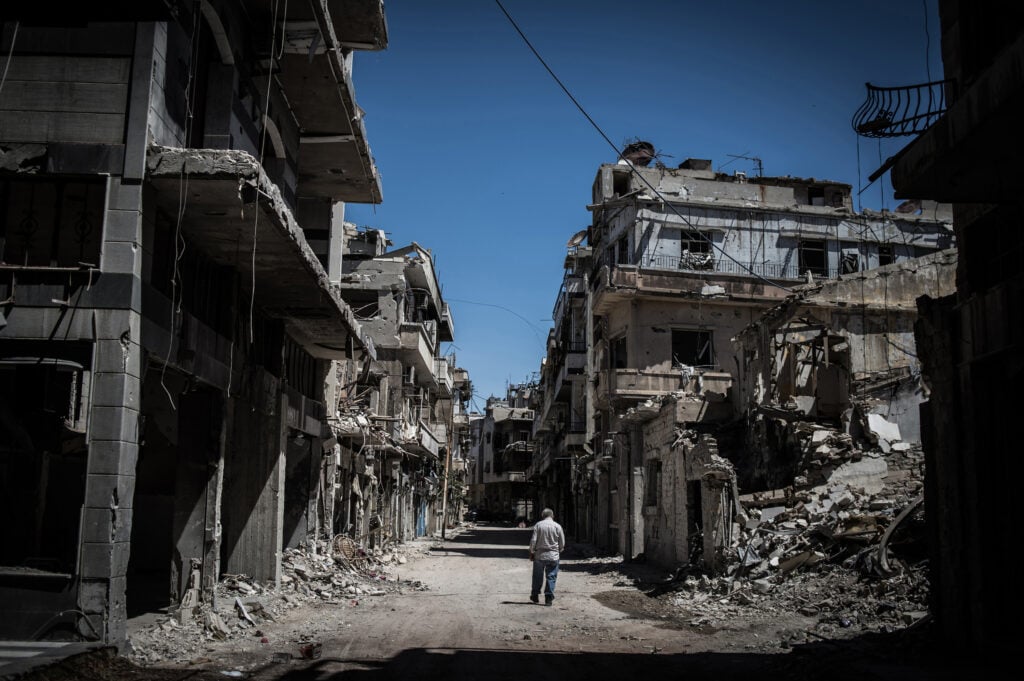 A Syrian refugee walks among severely damaged buildings in downtown Homs, Syria, on June 3, 2014.