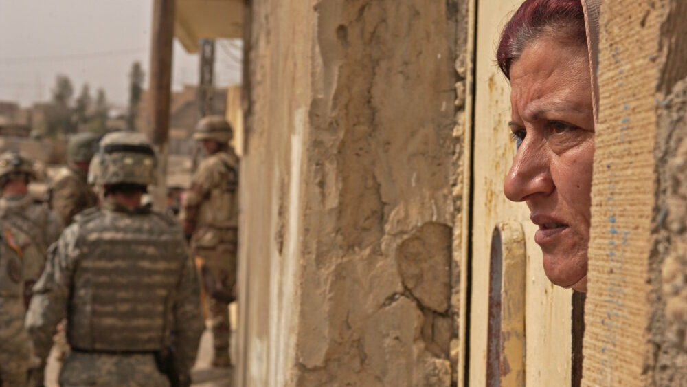 An Iraqi woman (not Shahinez) watches from the gate of her home in Mosul, Iraq.