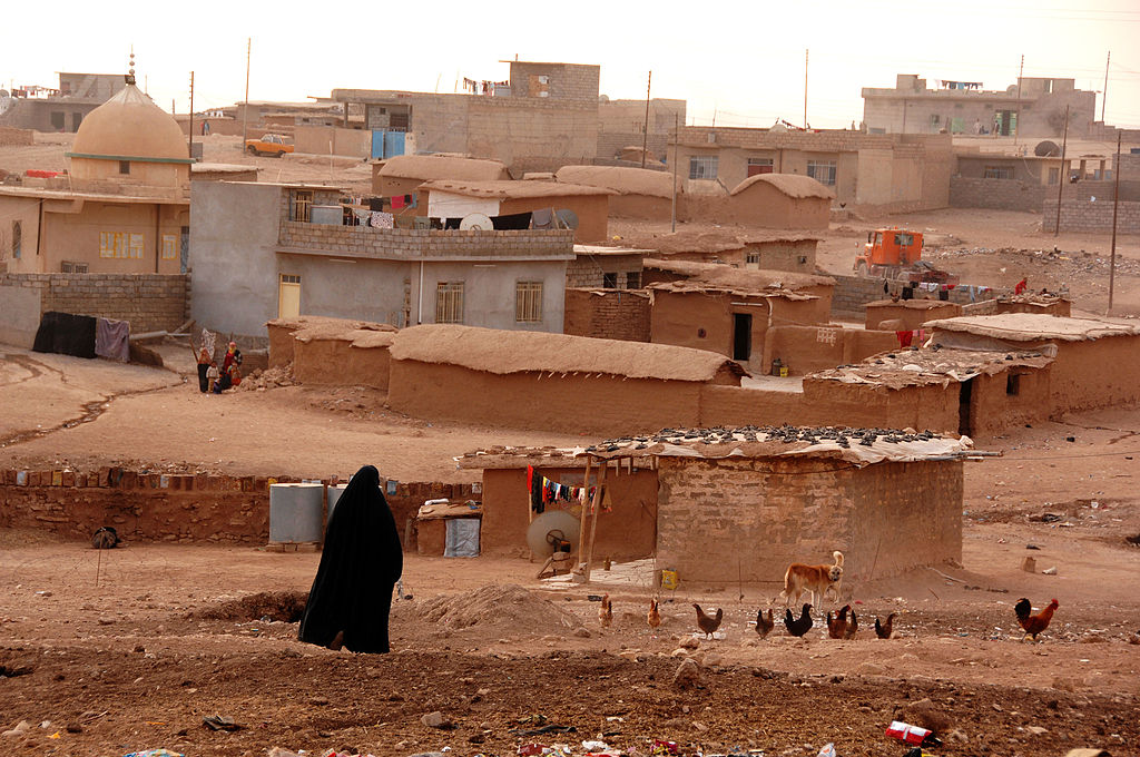 A woman walks through her village outside of Mosul, Iraq