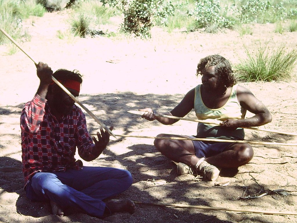 Men check their spears near Uluru