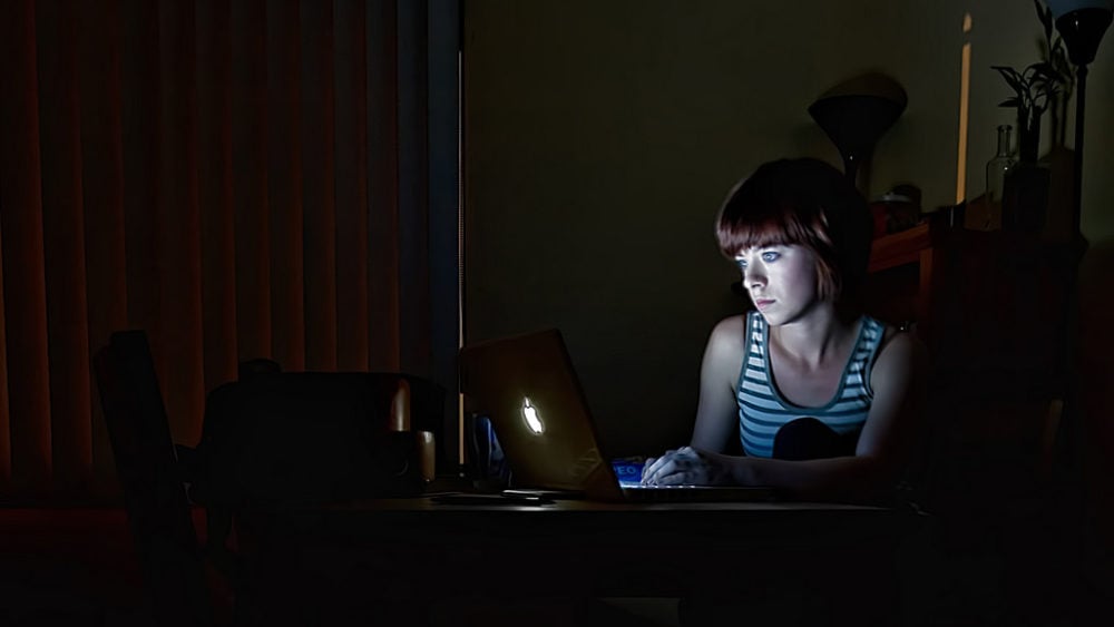 Woman in darkened room on computer
