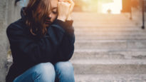 Sad girl sitting thoughtfully at the street. Image courtesy of Mission Australia.