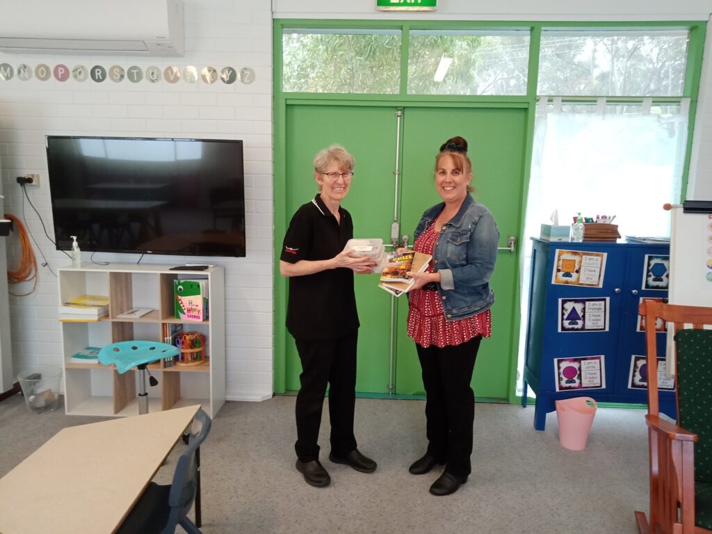 CRU staff member Katrina gives meal packs to Tina, principal of a local school.