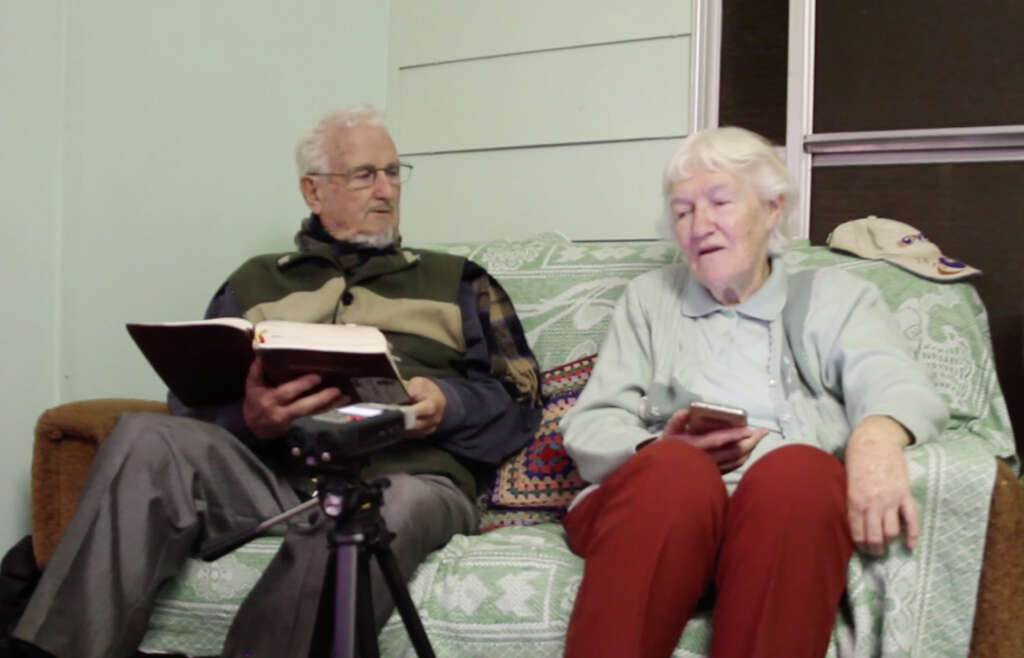 Brian and Dawn Hadfield being filmed reading the Bible in Pitjantjatjara