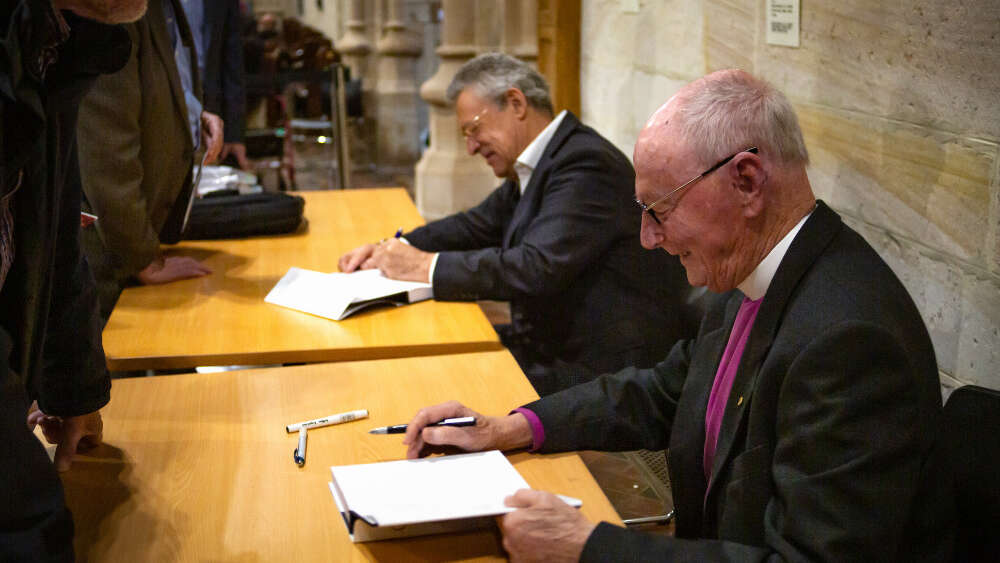 Harry Goodhew (front) and Stuart Piggin sign copies of the biography.
