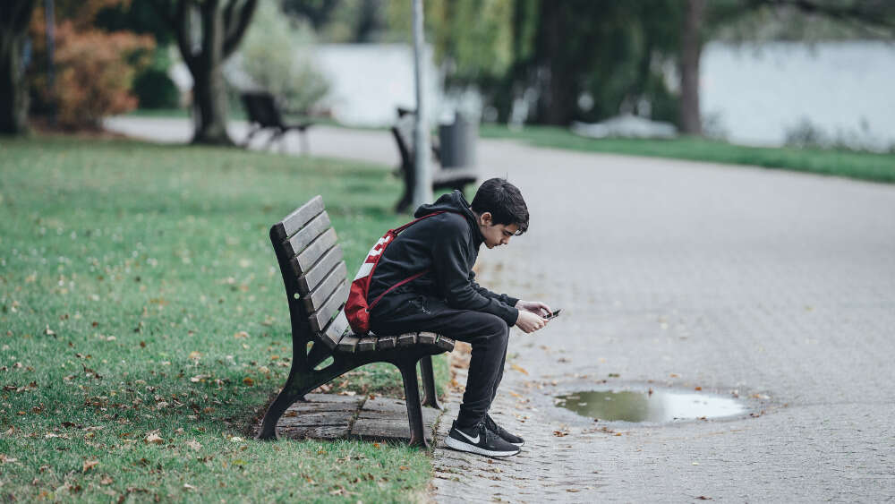 Boy on park bench looking at phone