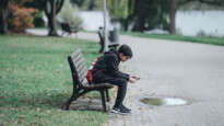 Boy on park bench looking at phone