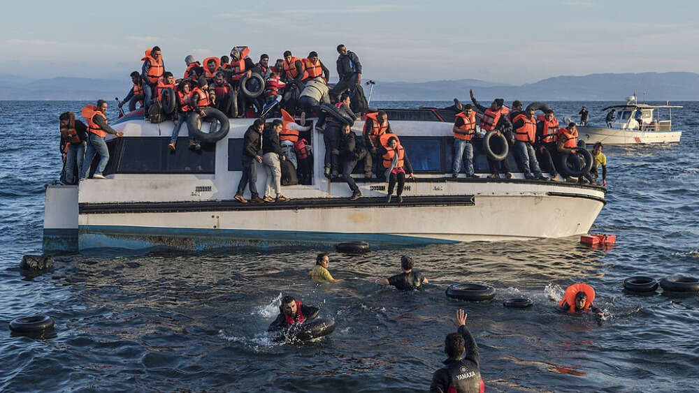 Syrian and Iraqi refugees arrive from Turkey to Skala Sykamias, Lesbos island, Greece. Volunteers (life rescue team - with yellow-red clothes) from the Spanish NGO Proactiva Open Arms help the refugees. Image: Ggia