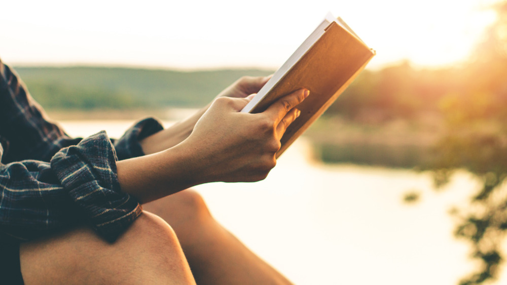 Woman reading book by lake