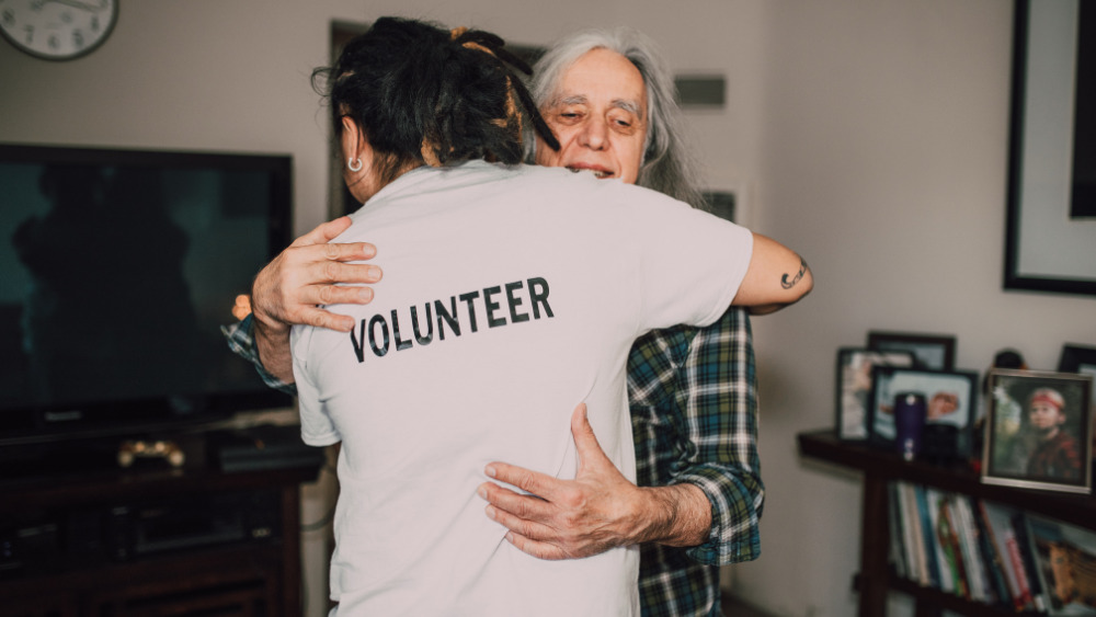 A volunteer hugs a client